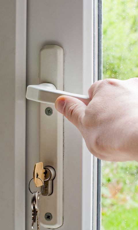 Hand operating a UPVC door handle with keys in the lock - UPVC door repair Belfast